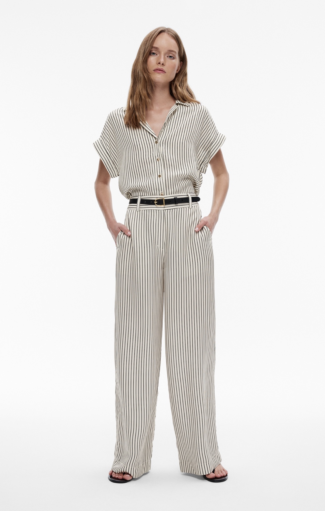 Woman in stripe short sleeve shirt, stripe pants, black leather belt and black leather sandals