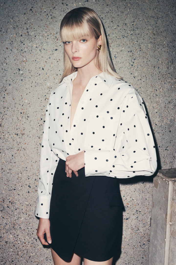 Woman in white embroidered spot shirt and black wrap mini skirt