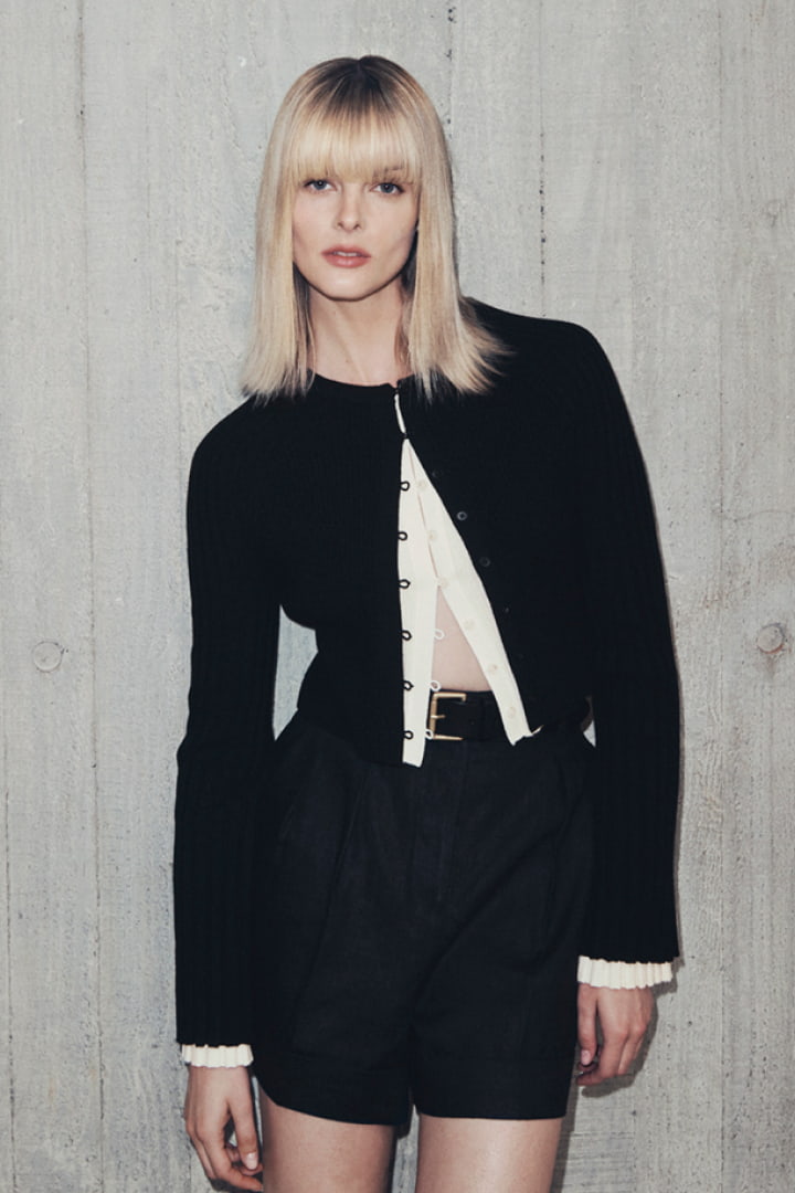 Woman in black wool blend button front knit, fresh white wool blend button front knit, black linen pleat short and black saskia leather belt