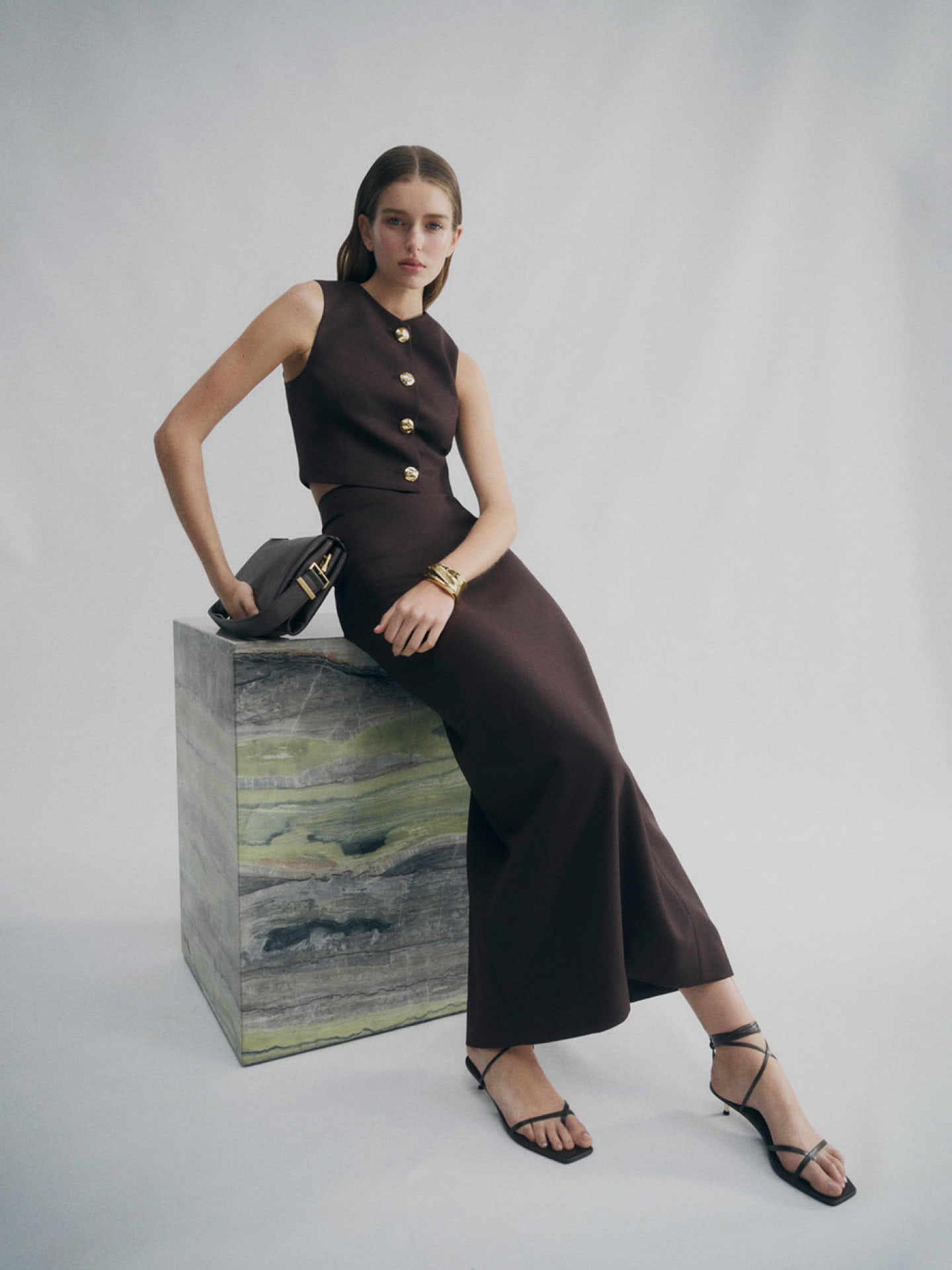 Woman in brown button detail vest, brown classic slimline skirt, brown blair tie up heel and brown liv leather bag